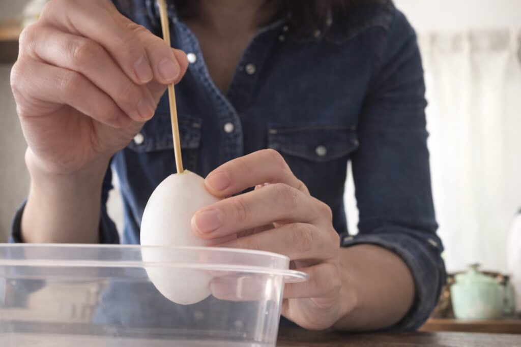卵の殻に竹串を差し込んでぐるぐるかき混ぜる