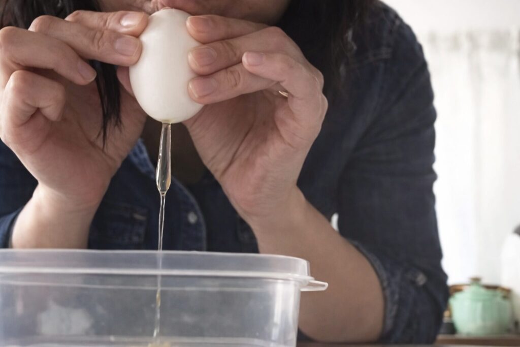 卵の殻の尖ったほうに息を吹き込む